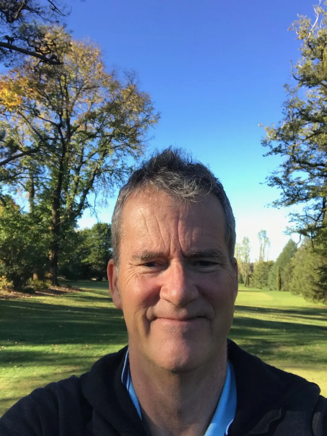 a photo of david with grass and trees behind him