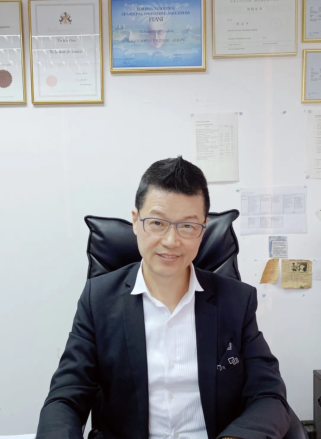 a man sitting in a black chair facing the camera and smiling