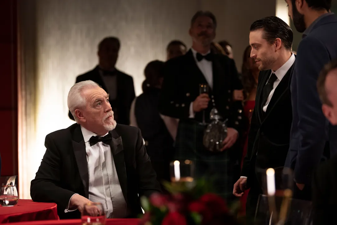 Brian Cox on set of Succession at a party with a man in a kilt in the background