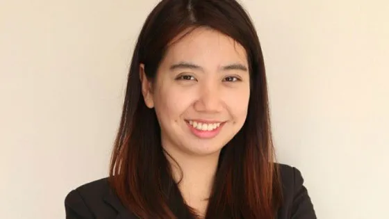 Araya Yotmongkol stands against a blank background smiling at the camera.