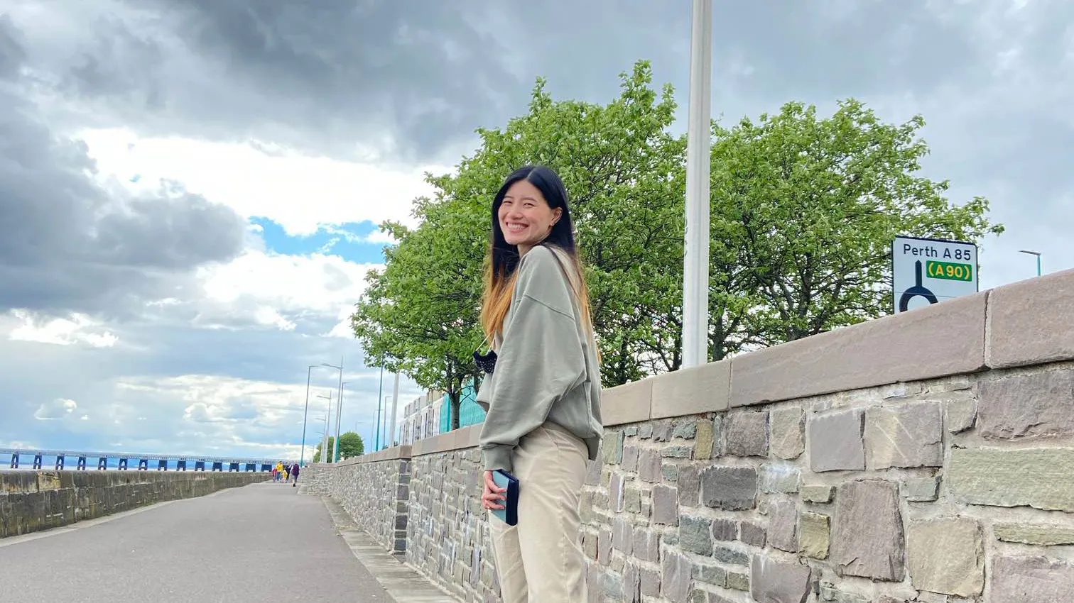 Adipa standing in front of a stone wall at the River Tay and the Rail bridge in the distance