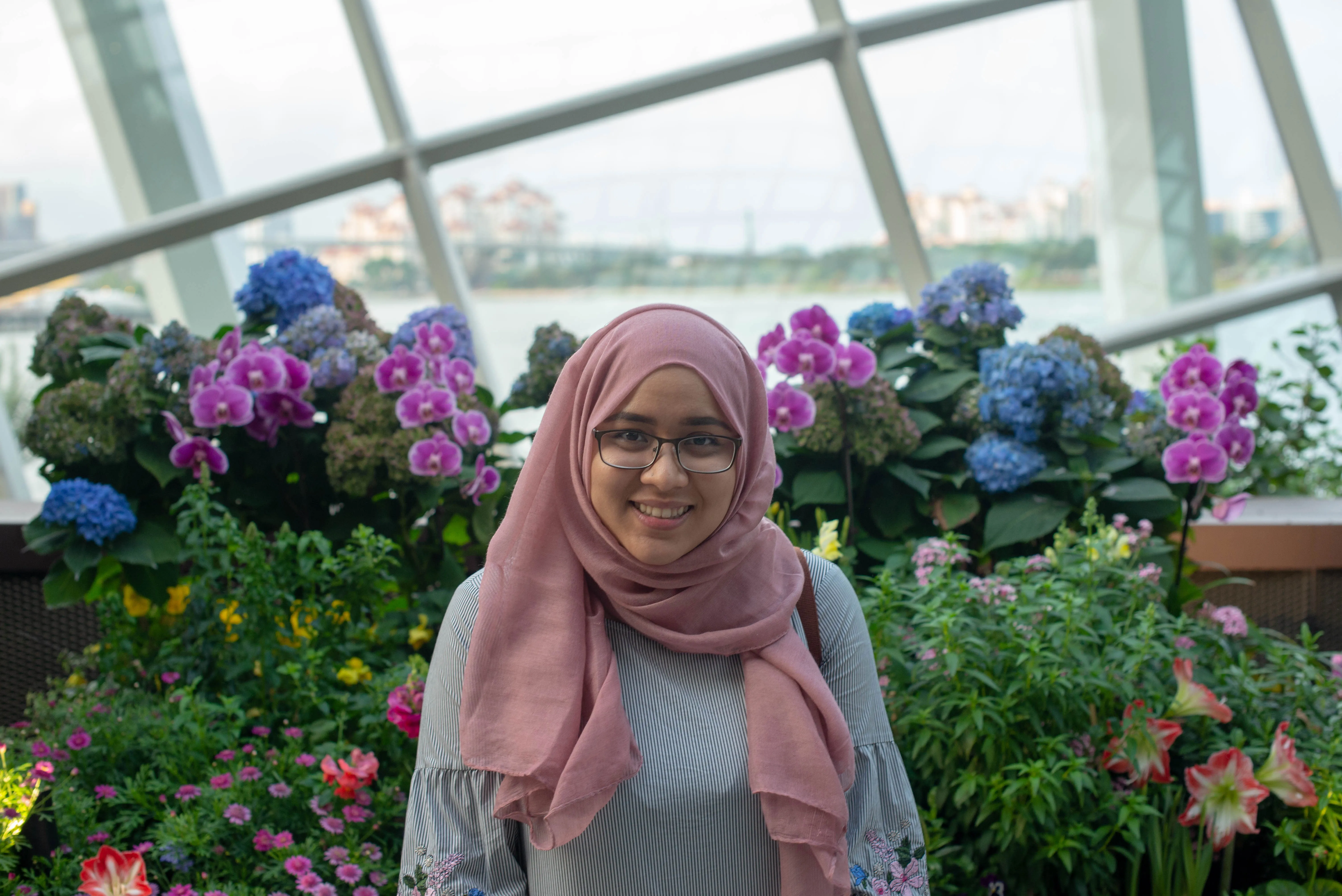 Ummi Jameel standing in front of pink and blue flowers