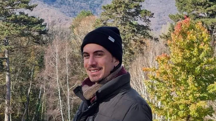 Dante Sosa outside surrounded by trees and mountains.