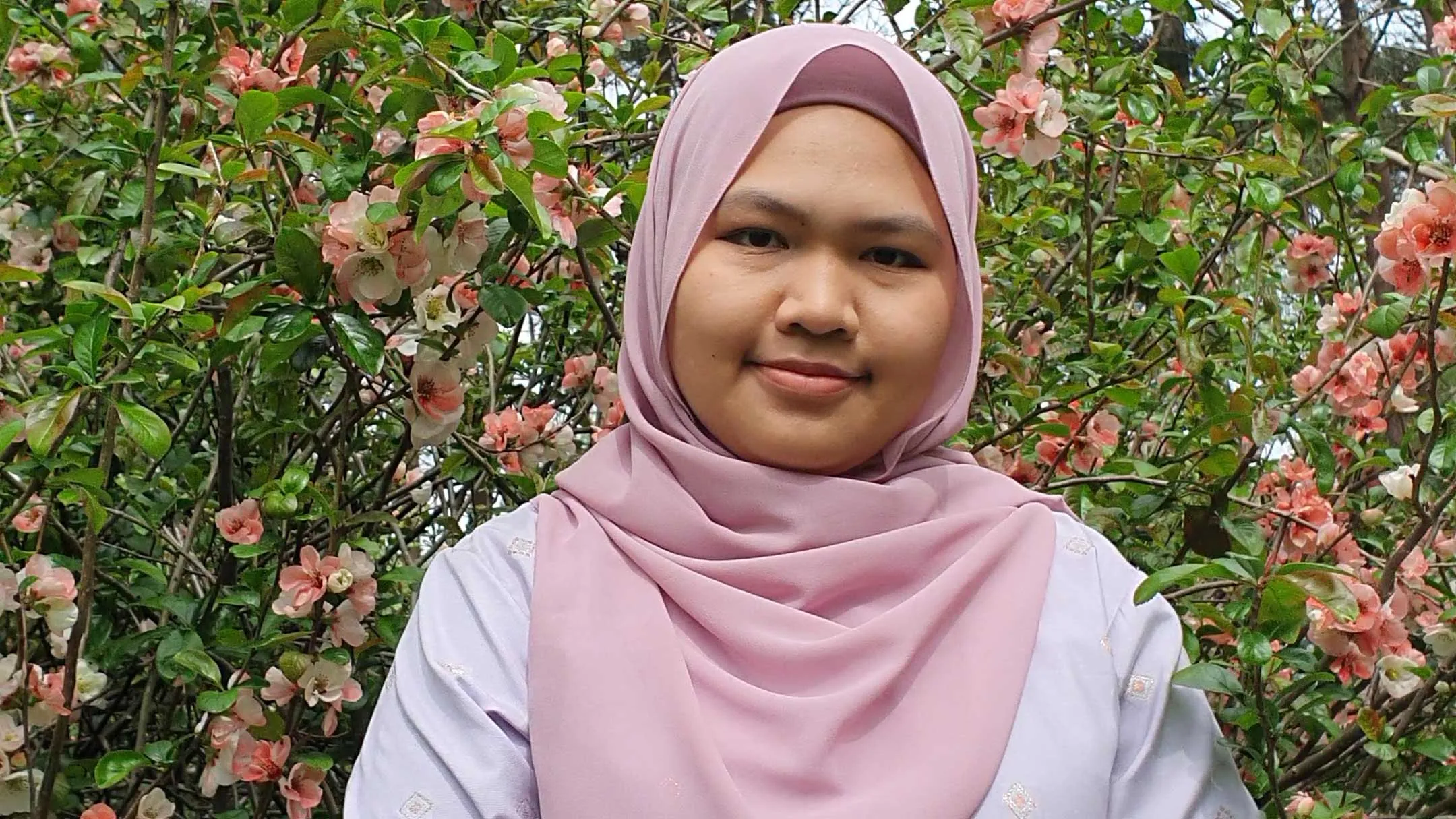 Raza Rahim standing in a garden with flowers behind her