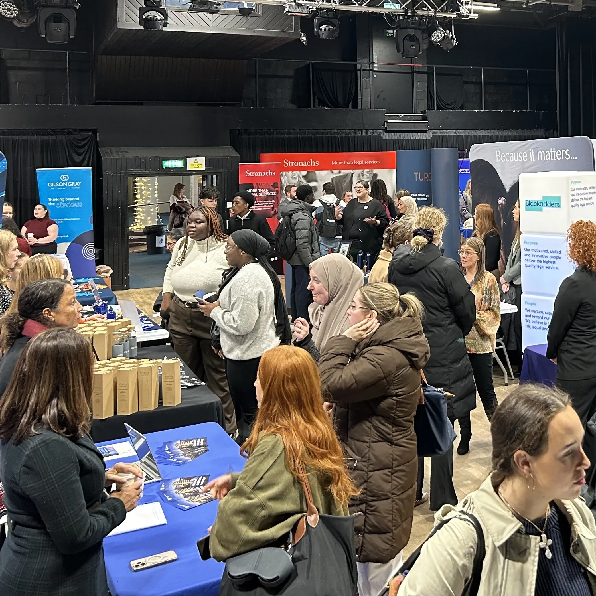 A group of people talking to employers at each empoyer table set up at an Employer fair 