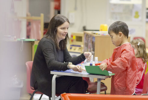 a woman teaching a small boy