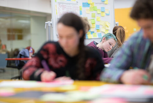 Students working on paper with lots of post it notes