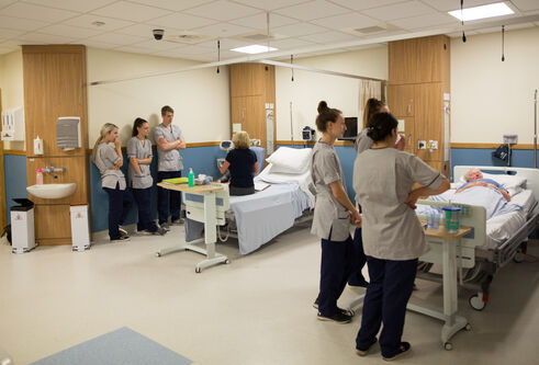 Student nurses attend to actors playing patients in a simulated ward