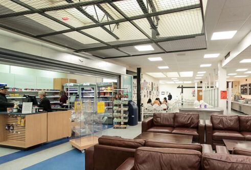 2 brown leather sofas, people sitting and some food on display to buy