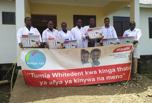 a group standing holding a sign for bridge 2 aid