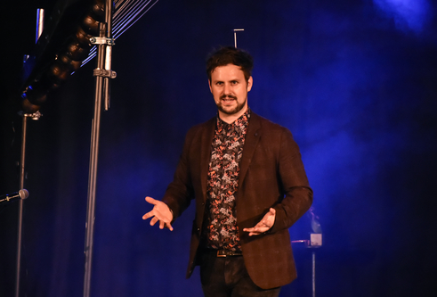 Kevin Quantum standing with his palms facing upwards and smiling