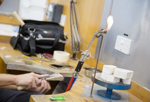 Hands working with a flame and blocks of material