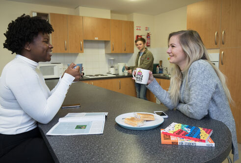 Students eating and drinking around kitchen table