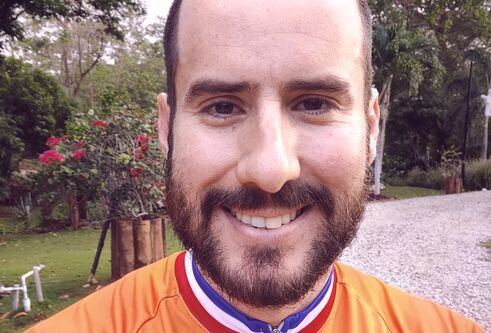 Alejandro smiling at camera wearing orange jumper