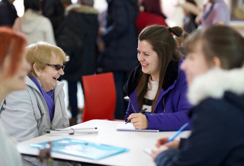 an older woman talking and laughing with a younger woman