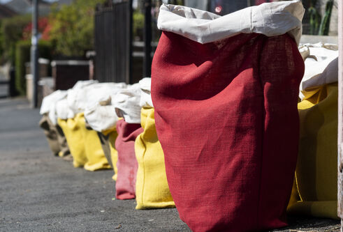 A line of cloth sacks in bright yellow and red all set in a row on a street
