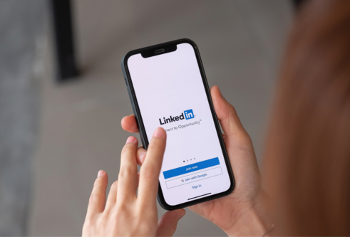 Image of person holding mobline phone looking at LinkedIn