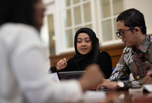 A couple of students sitting around a table looking at a laptop