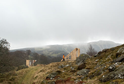 grey skies over rolling hills and two wooden structures facing one another on lower grassy part of hill
