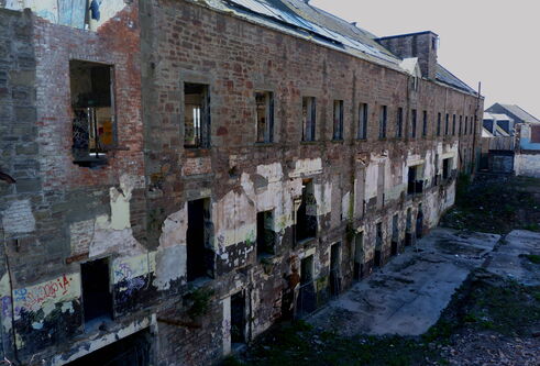 side view of a derelict two story jute mill. Window openings can be seen on the upper and lower levels