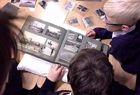 School pupils look over some archived photographs in a scrapbook