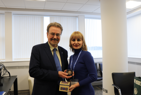 Professor Iain Gillespie and Professor Kamilla Mahrlamova standing side by side smiling in an office holding a brinze medal and a ornate box decorated with a traditional Ukrainian flower design