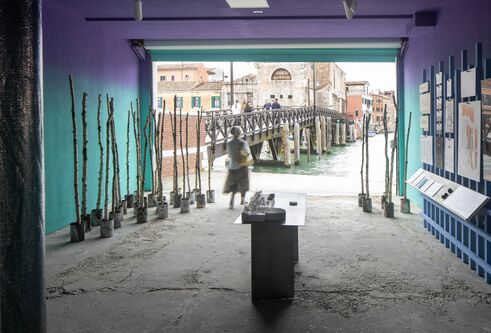 A figure is standing at the far end of a room with an open wall leading onto canals.
