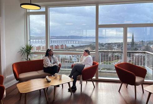  Two people sitting at the window of the Tower cafe with views of the River Tay and rail bridge