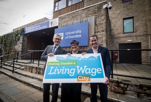 Professor Shane O'Neill, Councillor Lynne Short and Dr Jim McGeorge outside of the University's Tower Building with a sign to promote Dundee as a Living Wage city