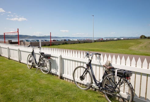 bikes alongside white fence looking out towards the river