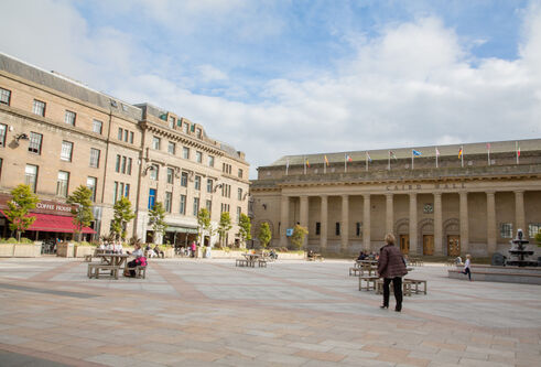 building with pillars in front of it opening out on to a square with buildings to the side