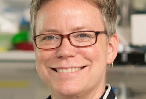 A woman with short hair and glasses, wearing a striped shirt.