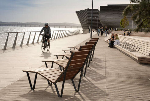 wooden deckchairs on boardwalk with cyclist coming past