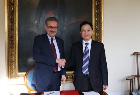 Two men in suits shaking hands and smiling