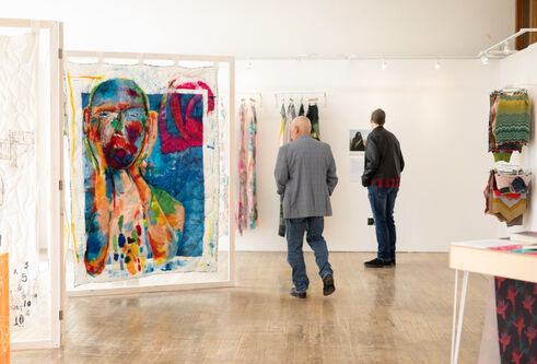 men looking at abstract art on white canvases