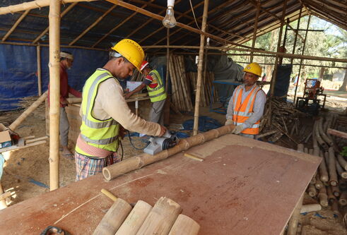 A construction worker prepares bamboo in a workshop