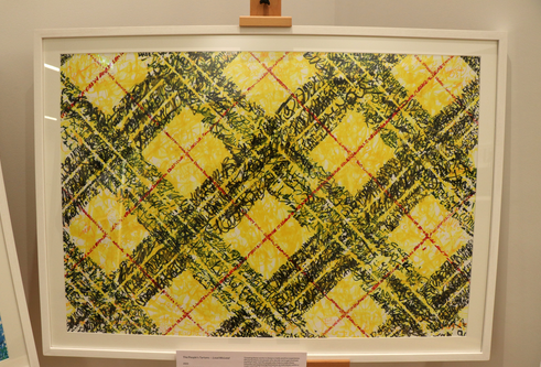 An image of yellow black and red tartan in a white frame on an easel