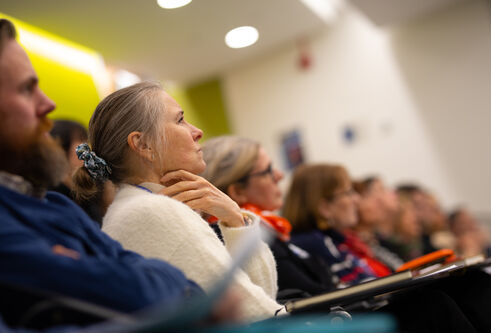A row of men and women in a lecture theatre listening to a talk.