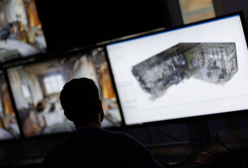 A man looks at multiple computer screens, which are out of focus