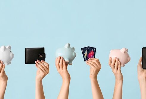 Hands in the air holding wallets and piggie banks