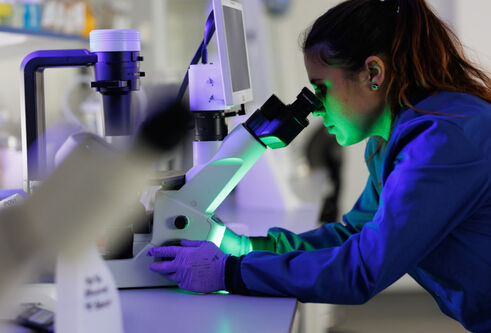 woman looking into microscope