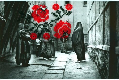 A black and white photograph of people in an alley, obscured by bright red thread