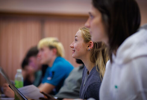 Students sitting in a lecture theatre looking up at the projection screen