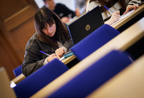 A student taking notes while in a lecture