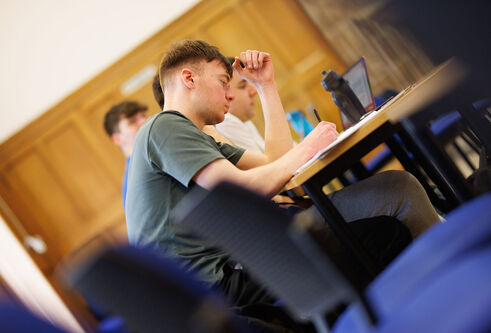A student taking notes in a lecture