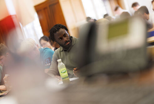 A student looking towards another student sitting in a lecture theatre