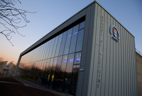The exterior of the School of Medicine library, with an orange sunset behind it