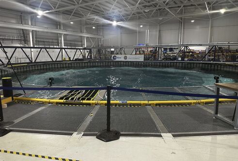 Large circular indoor pool with grills and barriers around it. Water is clearly moving and swelling in centre 