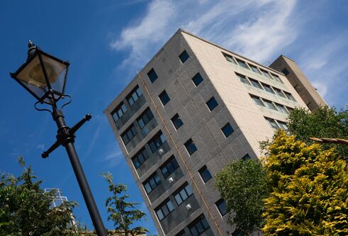 The School of Dentistry building against a blue sky. A Victorian-style street light is in the foreground.