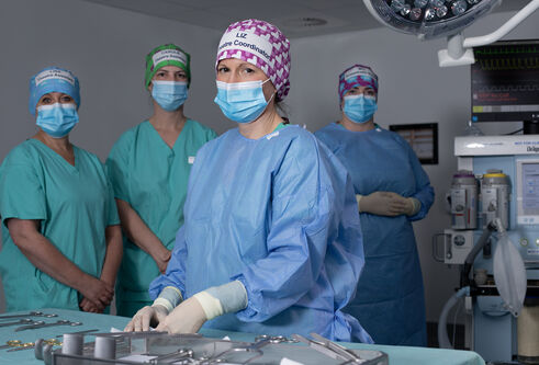 surgeons wearing hospital scrubs, masks and hair nets 